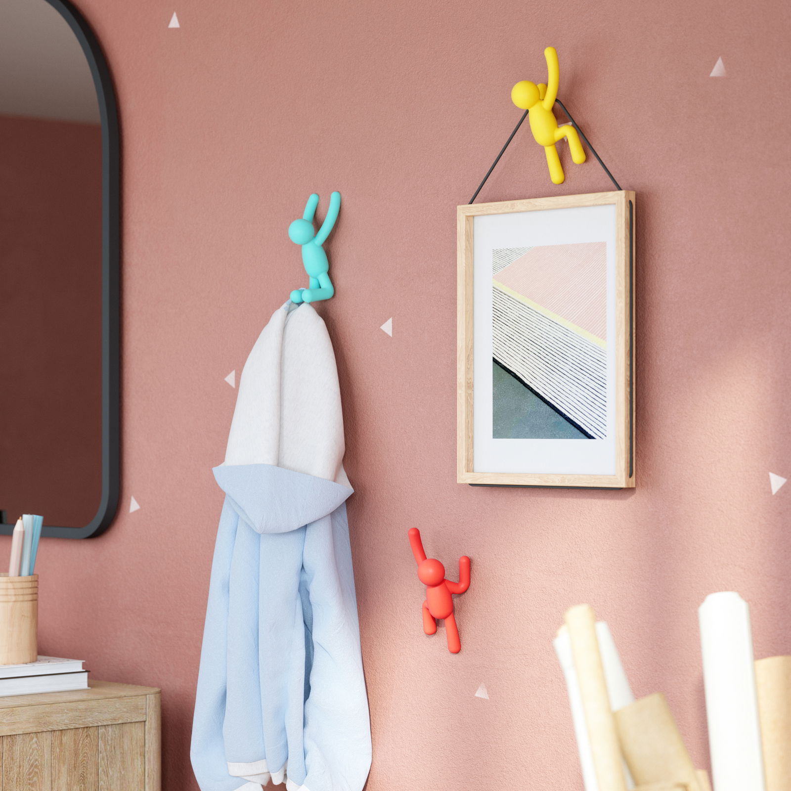 Wandhaken-Set BUDDY von Umbra in verschiedenen Farben, an einer Wand montiert, mit einem Handtuch und einem Bild, aus seitlicher Perspektive.