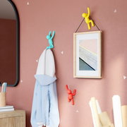 Wandhaken-Set BUDDY von Umbra in verschiedenen Farben, an einer Wand montiert, mit einem Handtuch und einem Bild, aus seitlicher Perspektive.
