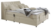 Beiges Boxspringbett mit verstellbarem Kopfteil, seitlicher Perspektive, dekoriert mit Kissen und Decke.