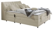 Beiges Boxspringbett mit verstellbarem Kopfteil, seitlicher Perspektive, dekoriert mit Kissen und Decke.