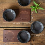 Vier anthrazitfarbene Miso-Schalen auf einem Holztisch, von oben betrachtet, mit zwei rechteckigen Untersetzern und einem Minzzweig.