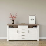 Weißes Sideboard mit brauner Oberseite, fünf Schubladen und zwei Türen, dekoriert mit einer Vase mit roten Zweigen und einem gerahmten Zitat, Frontalansicht.