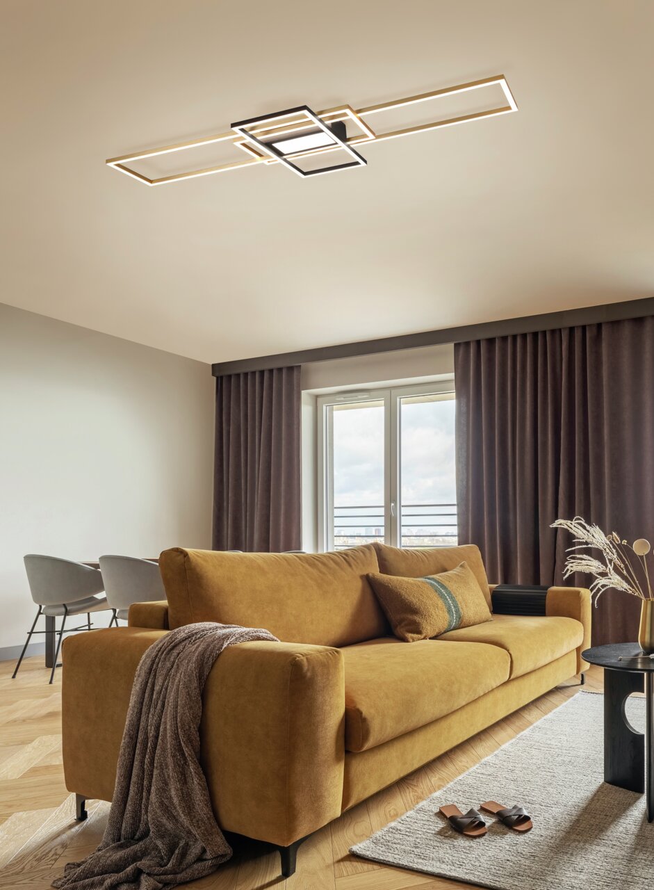 Moderne LED-Deckenleuchte in geometrischem Design, montiert an der Decke eines stilvoll eingerichteten Wohnzimmers mit einem senfgelben Sofa. Perspektive von unten.