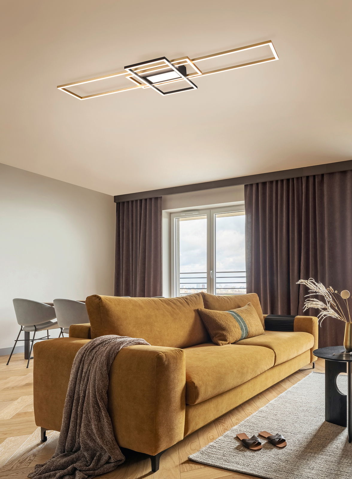 Moderne LED-Deckenleuchte in geometrischem Design, montiert an der Decke eines stilvoll eingerichteten Wohnzimmers mit einem senfgelben Sofa. Perspektive von unten.