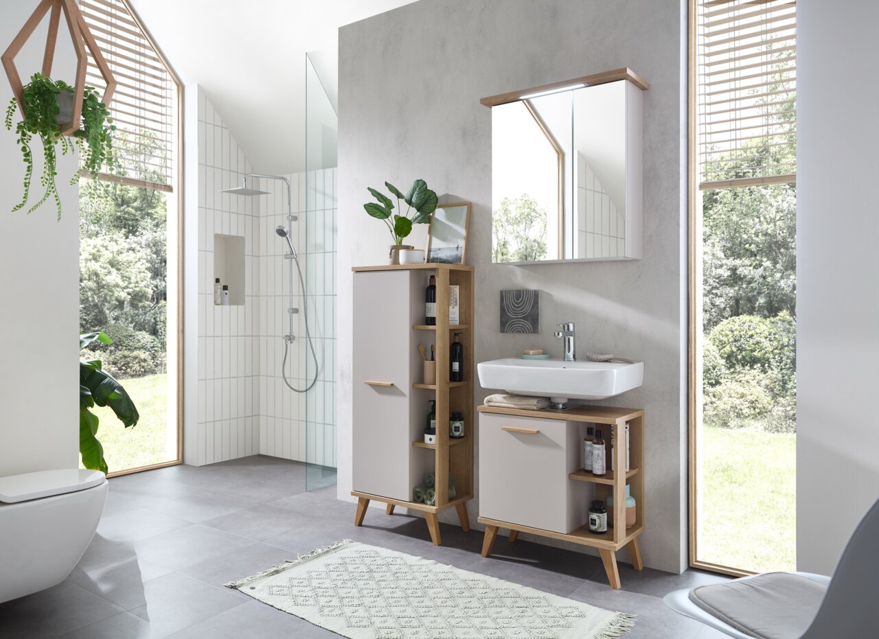 Moderner Midischrank im Badezimmer, frontal fotografiert, mit Holz- und weißen Elementen, umgeben von Pflanzen und einem Waschbecken.