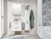 Moderne Waschtischlösung in einem Badezimmer, frontal fotografiert. Enthält einen weißen Waschtisch mit zwei Schubladen, einen Spiegel und einen hohen Schrank. Dekoriert mit Handtüchern und Pflanzen.