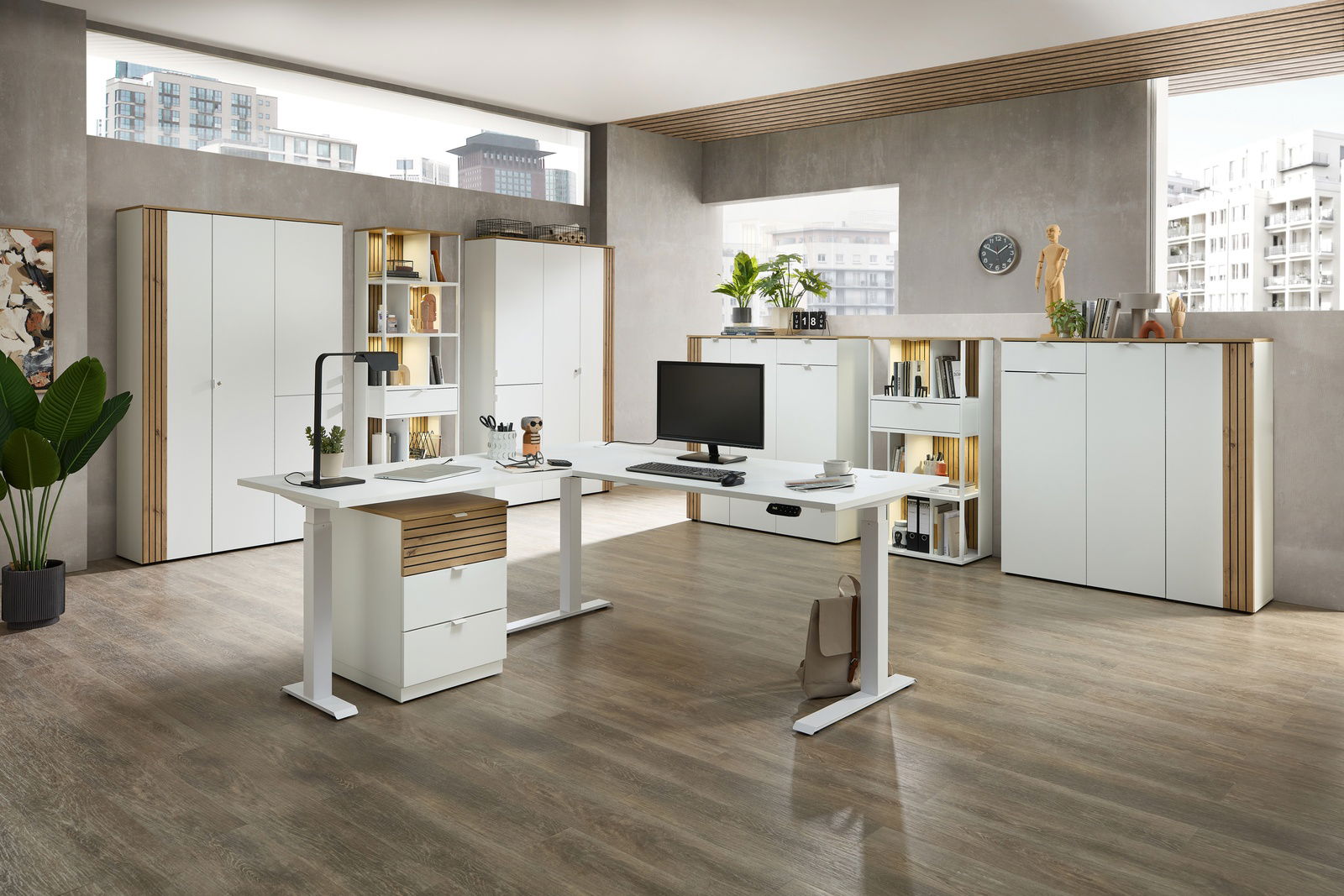 Moderner Büroraum mit weißem Eckschreibtisch, Aktenschränken und Regalen, aus der Perspektive des Raumeingangs fotografiert.