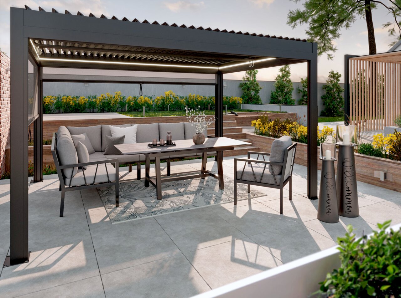Amatio Select Pavillon PARA Moderne Pergola mit verstellbaren Lamellen und integrierter LED-Beleuchtung über einer grauen Outdoor-Lounge und Esstisch auf der Terrasse, Frontansicht in leichter Schrägperspektive