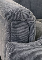 Nahaufnahme einer grauen, strukturierten Polsterung eines Sofas, Perspektive von der Armlehne.