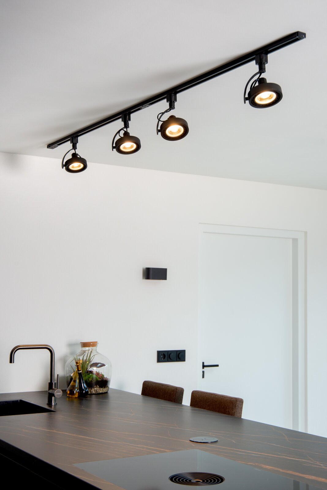 Zwarte plafondspot DORIAN TRACK met vier verstelbare lampen, gemonteerd boven een moderne keuken. Aanzicht van onderaf.