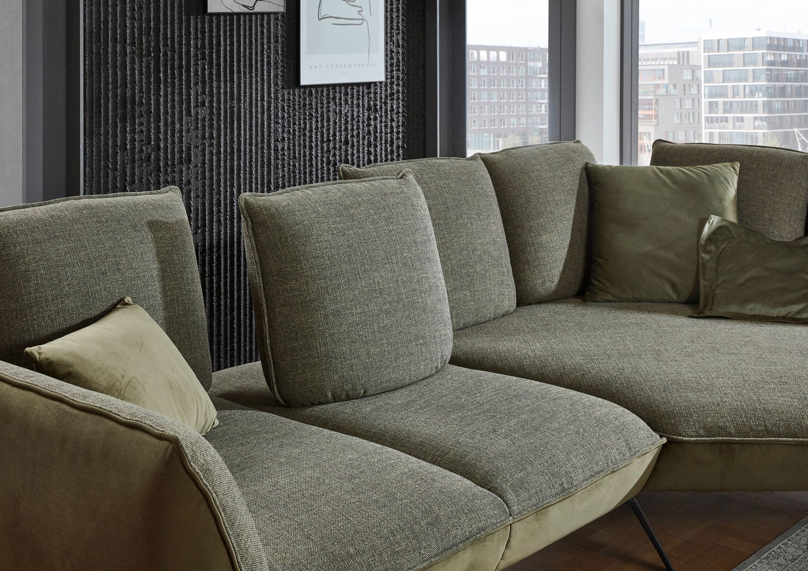 Moderano Longchair-combinatie ALPHA Moderano Longchairkombination ALPHA in einer modernen Wohnumgebung, seitliche Perspektive auf das grüne Sofa mit mehreren Kissen.