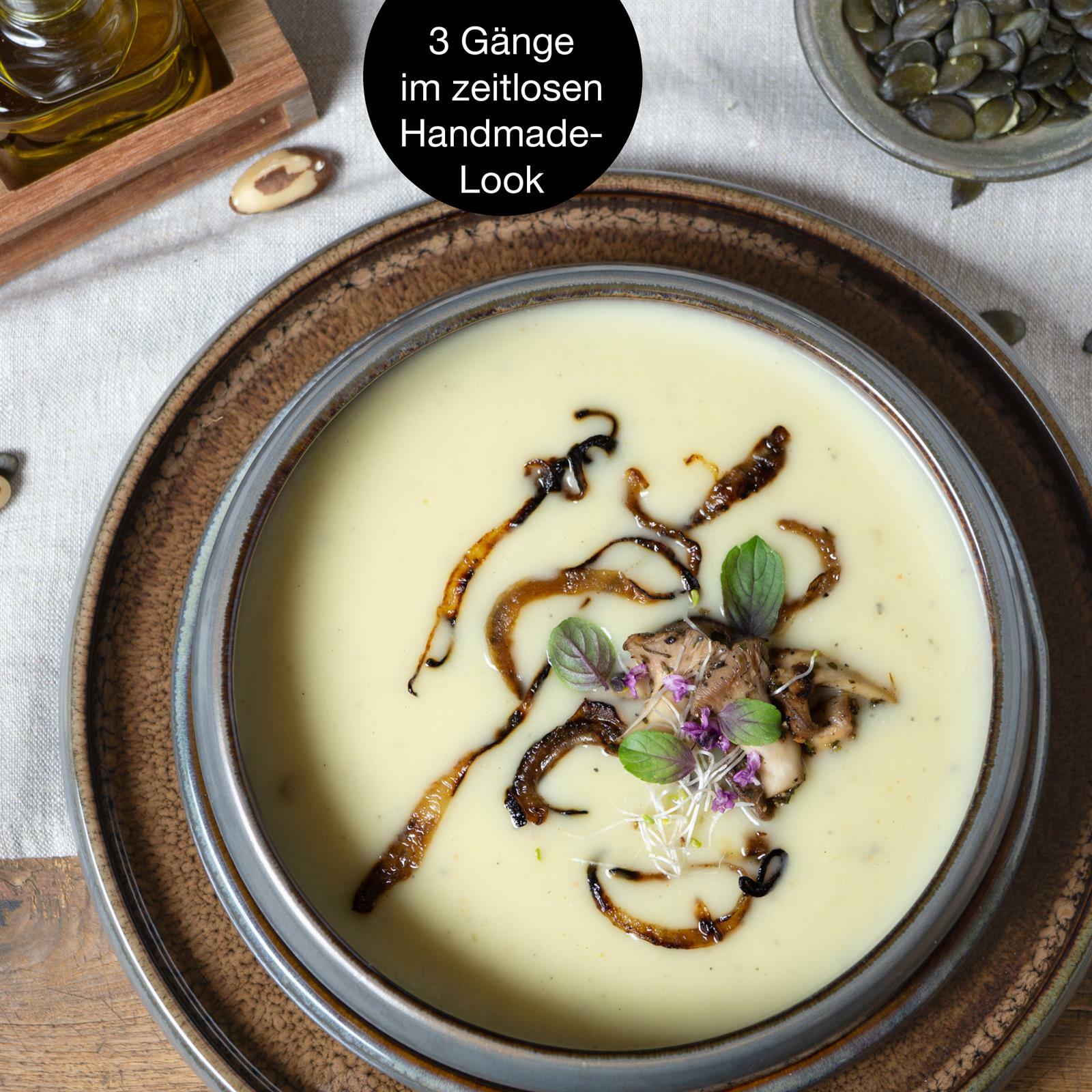 Vogelperspektive auf einen Teller mit cremiger Suppe, garniert mit gebratenen Zwiebeln und frischen Kräutern, serviert auf einem rustikalen, braunen Tafelservice.