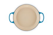 Runde, cremefarbene Auflaufform mit blauen Griffen, Ansicht von oben