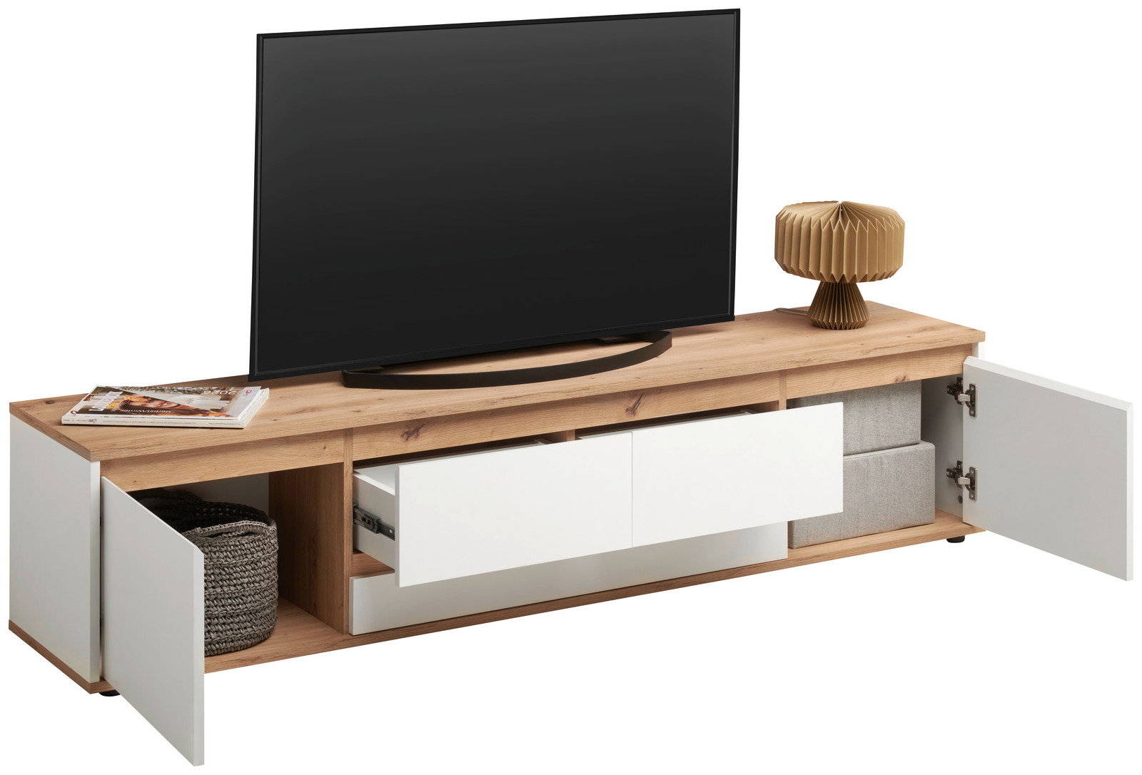 XL-TV-Lowboard aus Holz mit offenen Schubladen und Türen, von vorne betrachtet. Auf der Oberseite steht ein großer Fernseher, daneben eine Lampe und Zeitschriften.