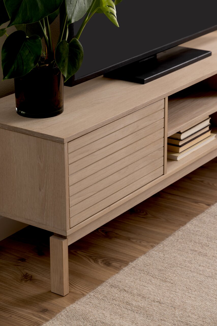 TV-Lowboard aus hellem Holz mit Pflanzen und Büchern, seitliche Perspektive