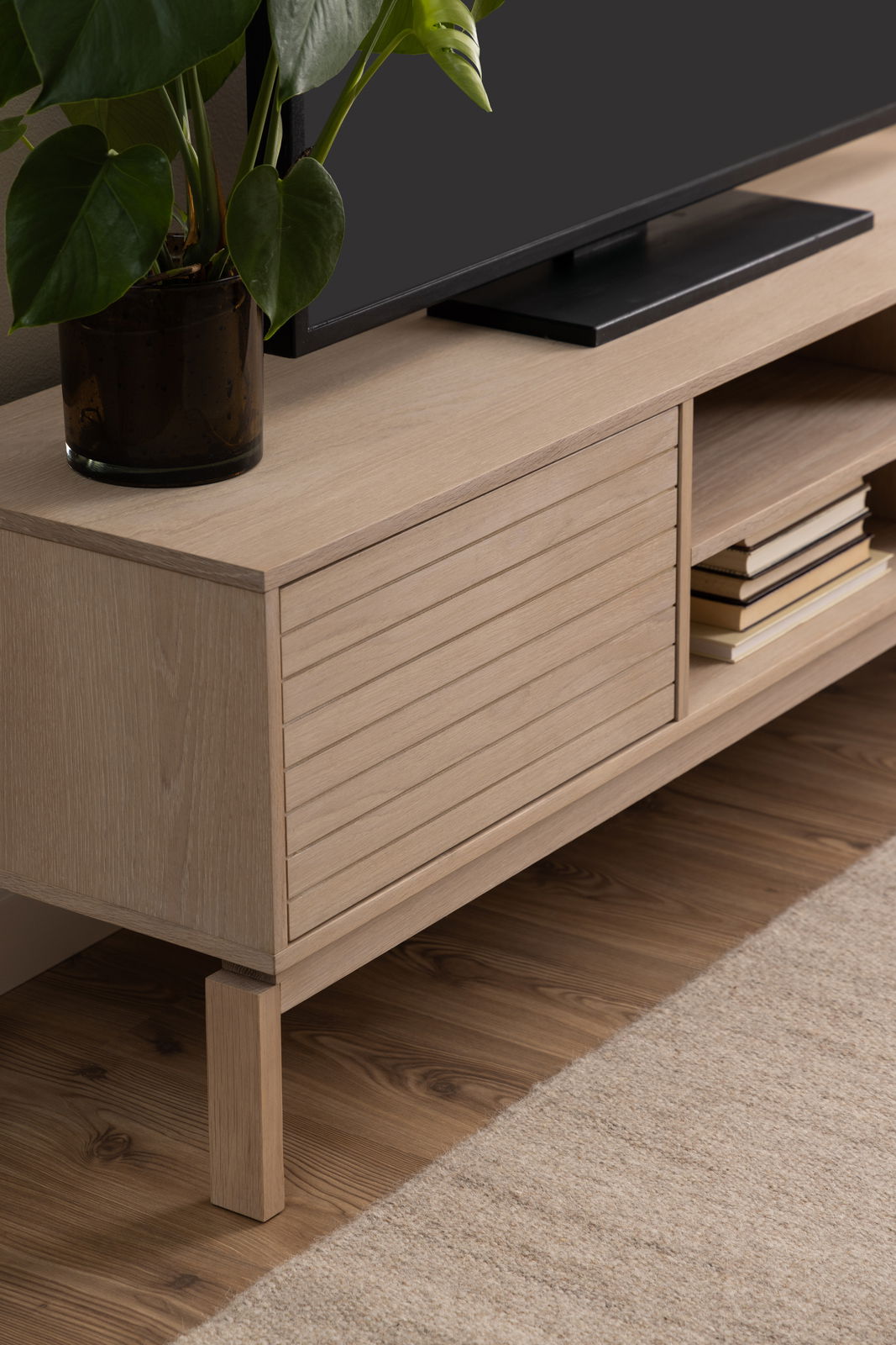 TV-Lowboard aus hellem Holz mit Pflanzen und Büchern, seitliche Perspektive