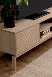 TV-Lowboard aus hellem Holz mit Pflanzen und Büchern, seitliche Perspektive