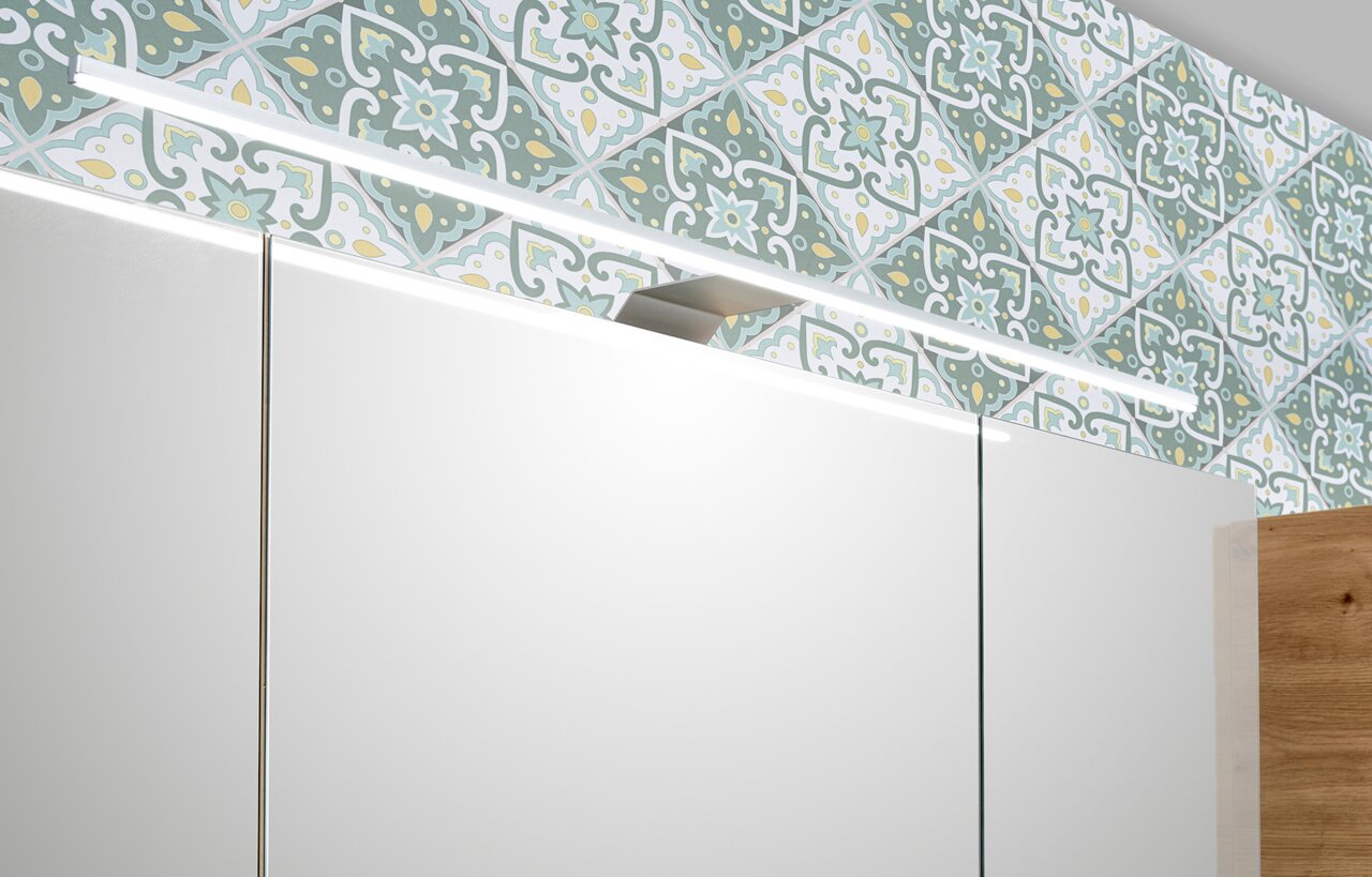 Close-up van een badkamercombinatie met moderne ledverlichting en decoratieve tegels op de achtergrond, gezien vanaf de voorkant.
