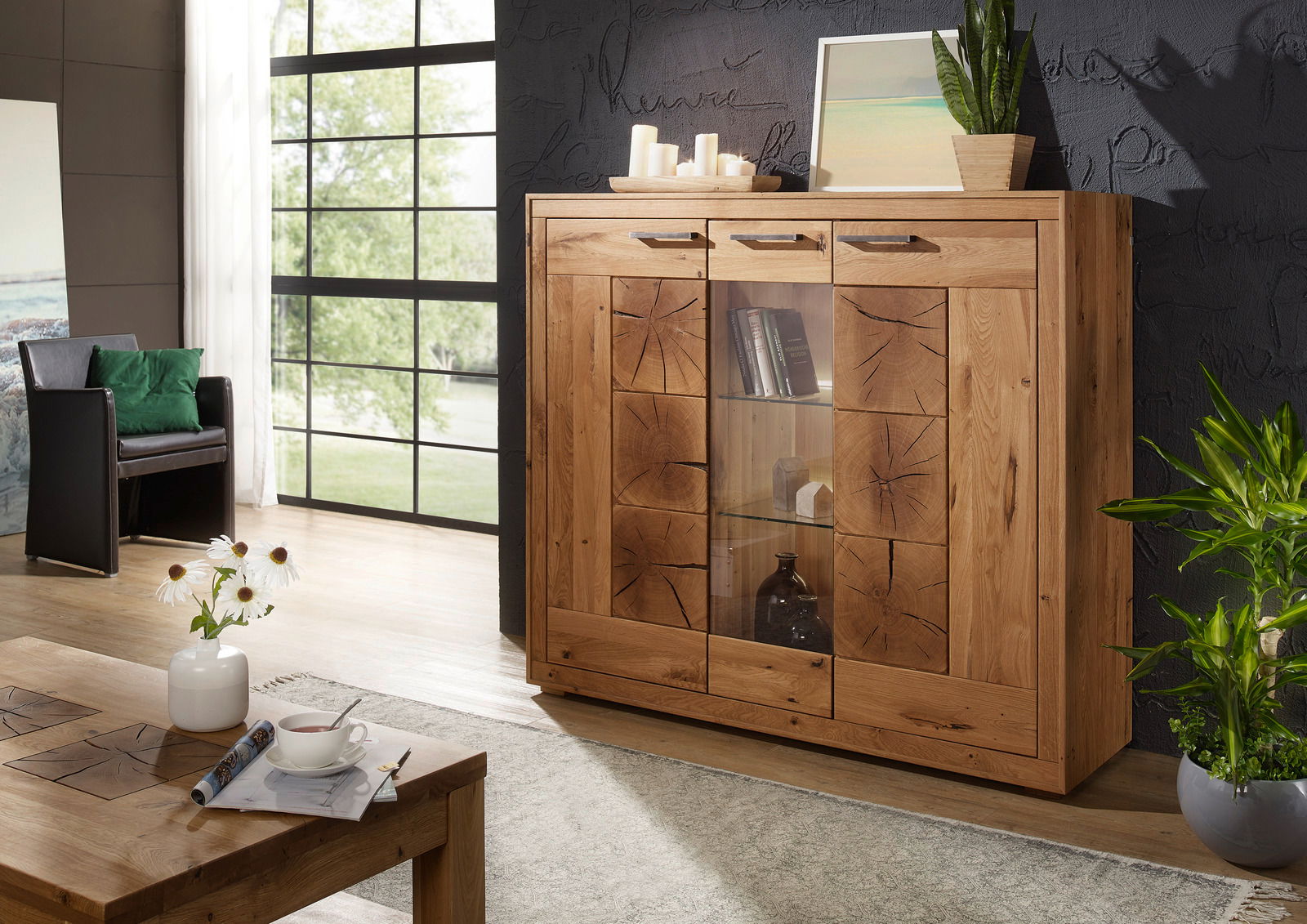 Landscape Highboard II MERAN Hochwertiges Highboard aus Holz mit Glaseinsätzen, dekoriert mit Pflanzen und Kerzen, in einem modernen Wohnzimmer. Frontalansicht.