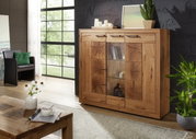 Hochwertiges Highboard aus Holz mit Glaseinsätzen, dekoriert mit Pflanzen und Kerzen, in einem modernen Wohnzimmer. Frontalansicht.