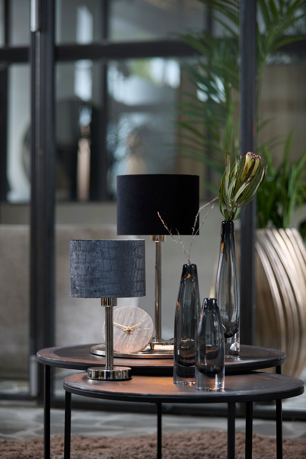 Moderner Lampenschirm in elegantem Schwarz auf einem Tisch, umgeben von stilvollen Dekorationsobjekten, seitliche Perspektive.