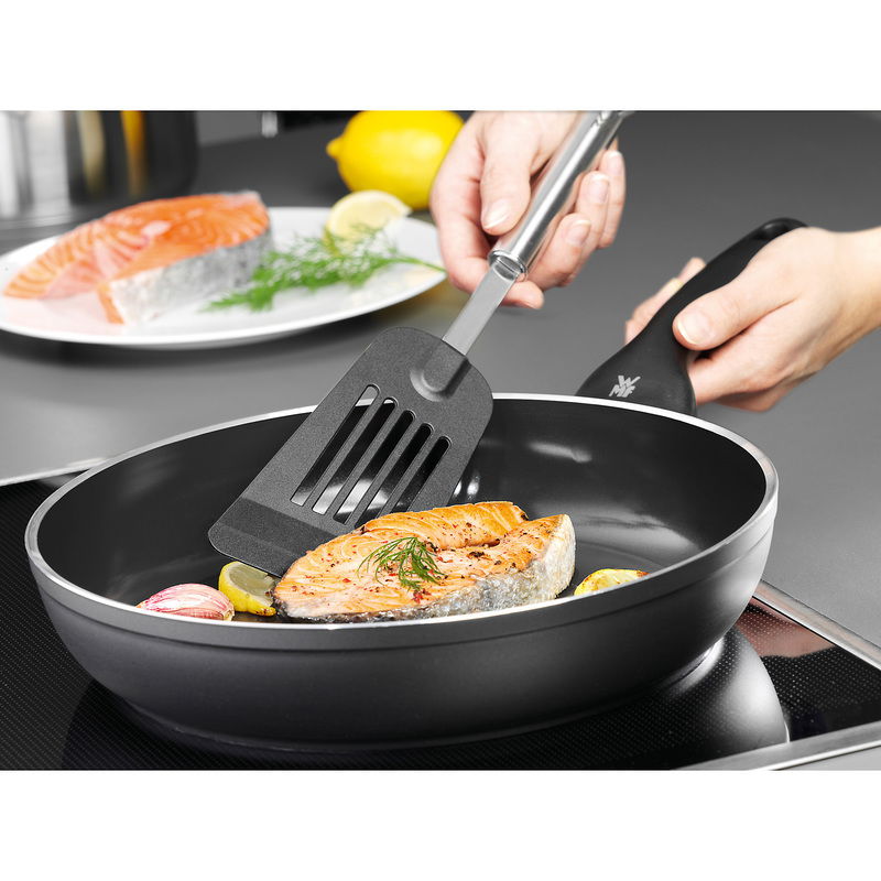 WMF Pfannenwender PROFI PLUS Nahaufnahme eines Wenders PROFI PLUS, der in einer Pfanne ein Stück Lachsfilet wendet. Perspektive von oben.