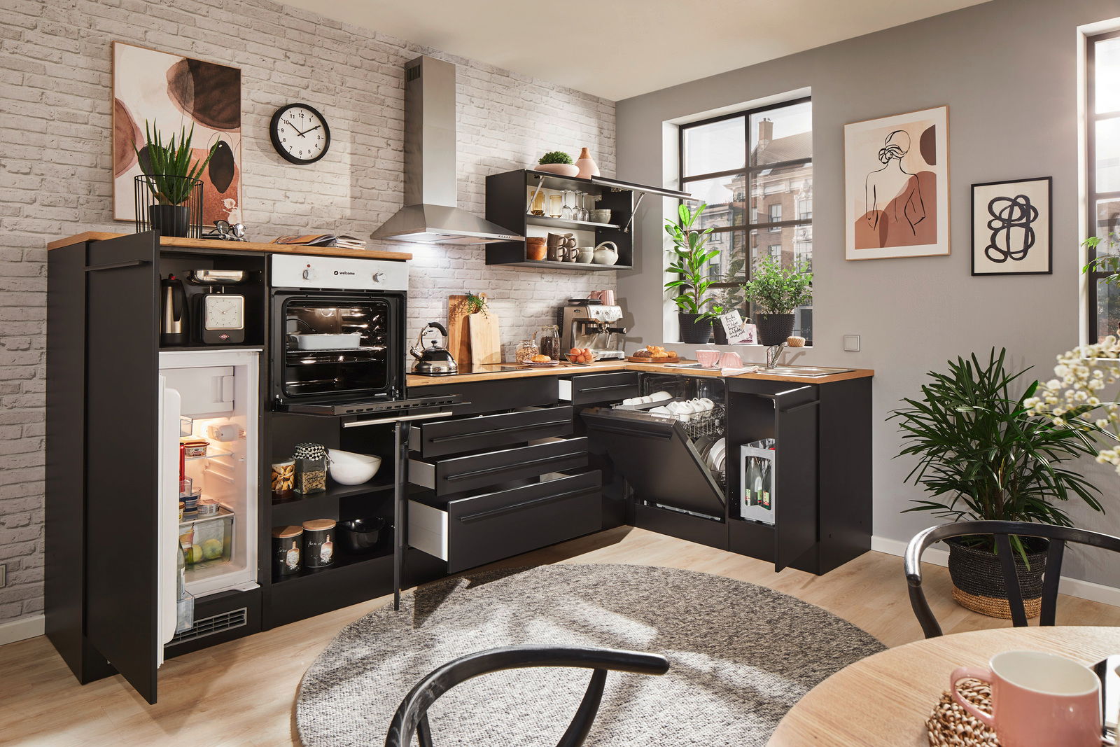 Moderne Küche mit Eckunterschrank, Kühlschrank, Backofen und Geschirrspüler in schwarzem Design, fotografiert aus einer leicht erhöhten Perspektive.