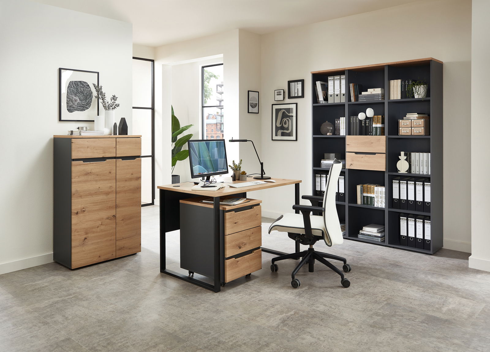 Voleo Regal schmal DETROIT Moderne Büromöbel in einem hellen Raum, bestehend aus einem Schreibtisch mit Rollcontainer, einem Aktenschrank und einem Regalschrank, aus Holz und Metall, seitliche Perspektive.