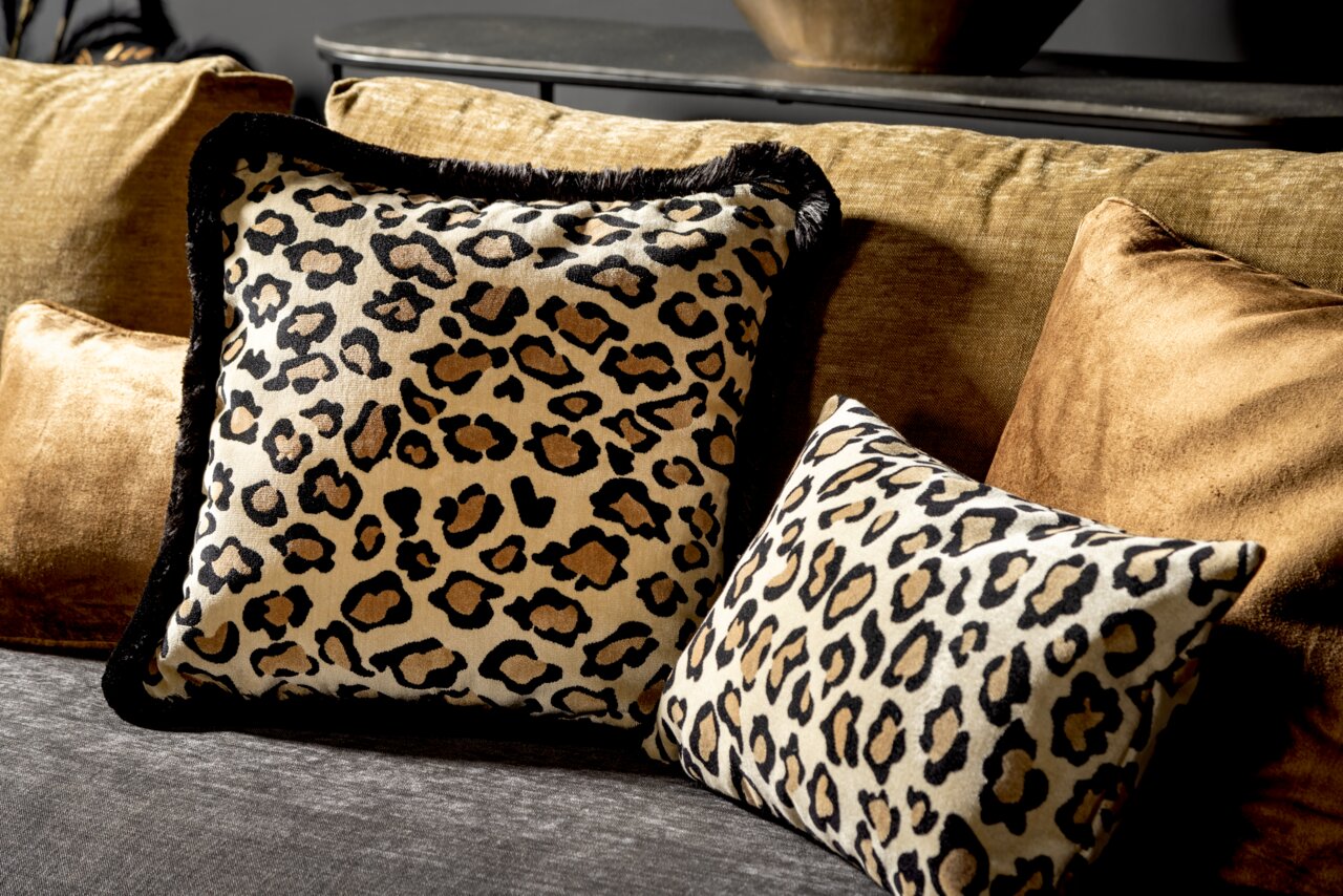 Zwei Dekokissen mit Leopardenmuster auf einem Sofa, fotografiert aus einer seitlichen Perspektive.