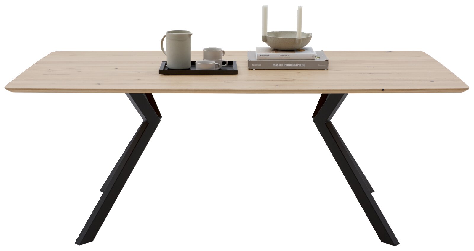 Moderne houten eettafel met een zwart metalen onderstel, gezien vanaf de voorkant, versierd met serviesgoed en boeken.