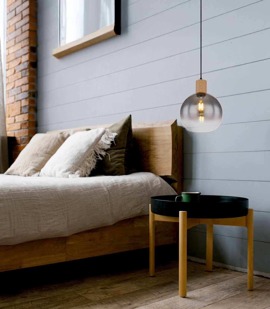 Moderne Hängeleuchte mit rundem, transparentem Glasschirm und Holzdetails, seitliche Perspektive im Schlafzimmer.