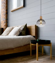 Moderne Hängeleuchte mit rundem, transparentem Glasschirm und Holzdetails, seitliche Perspektive im Schlafzimmer.