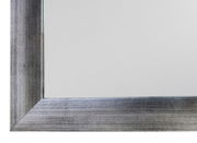 Nahaufnahme eines rechteckigen Spiegels mit silbernem Rahmen, perspektivisch von der Ecke aus gesehen.