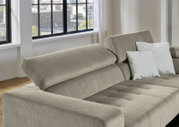 Beiges Cord-Ecksofa mit verstellbaren Rückenlehnen und hellen Kissen in modernem Wohnzimmer, schräg von vorne links fotografiert.