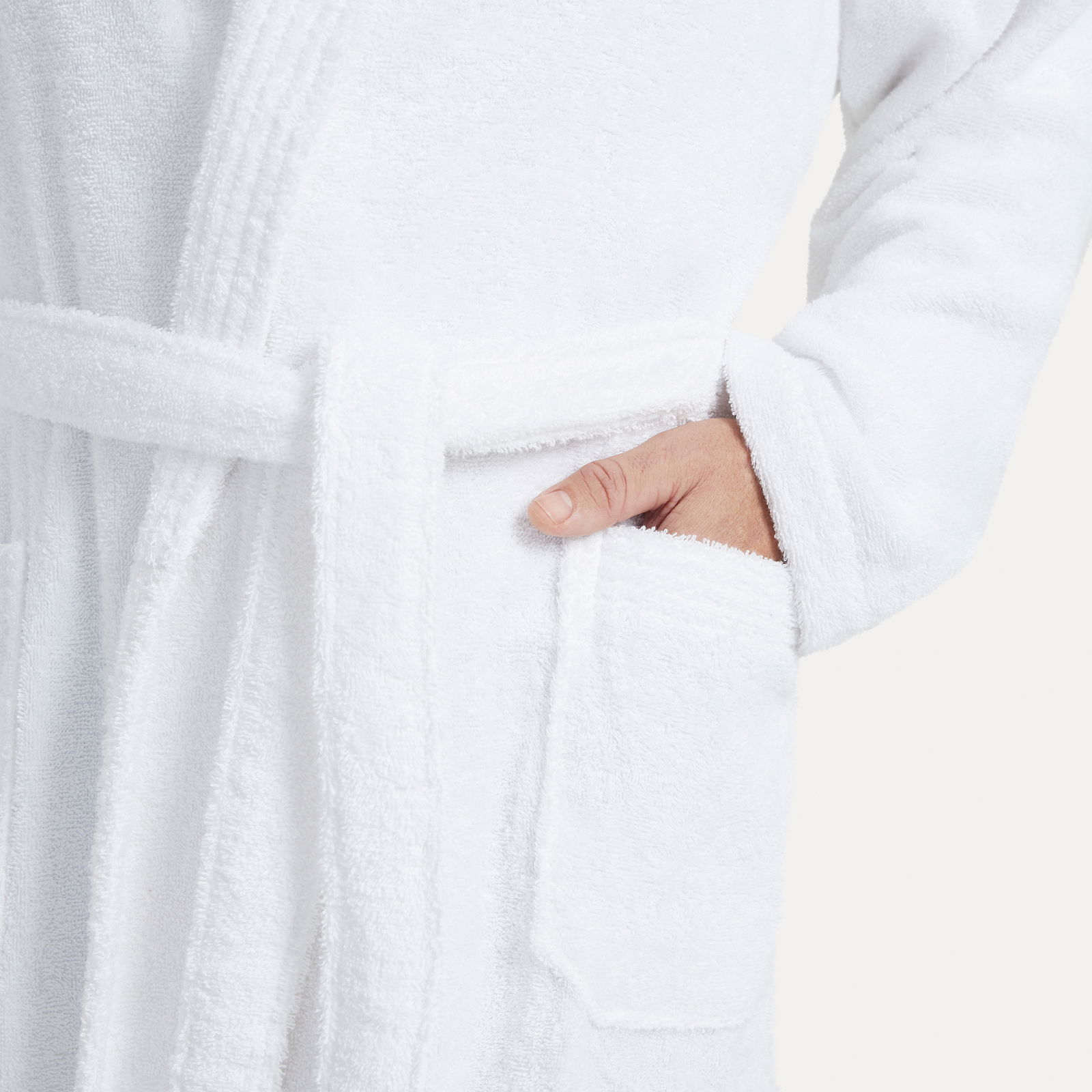 MÖVE Bademantel Schalkragen S HOMEWEAR BASIC Nahaufnahme eines weißen Bademantels mit Schalkragen, einer Hand in der Tasche und einem Gürtel um die Taille, von der Seite betrachtet.