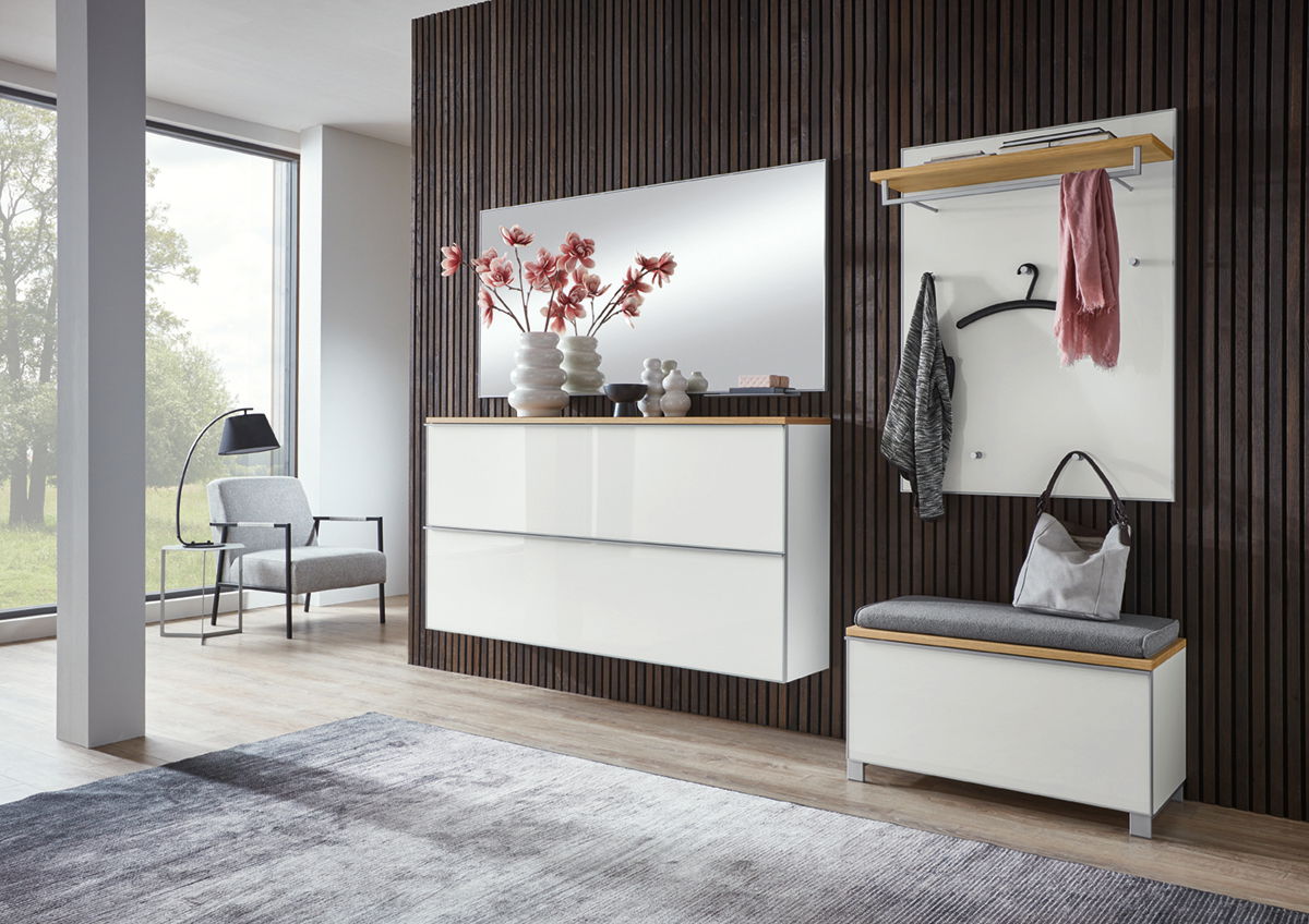Moderne Garderobeneinrichtung mit weißem Hängeschuhschrank, Spiegel und Garderobenbank in einem stilvollen Raum mit Holzverkleidung, seitliche Perspektive.
