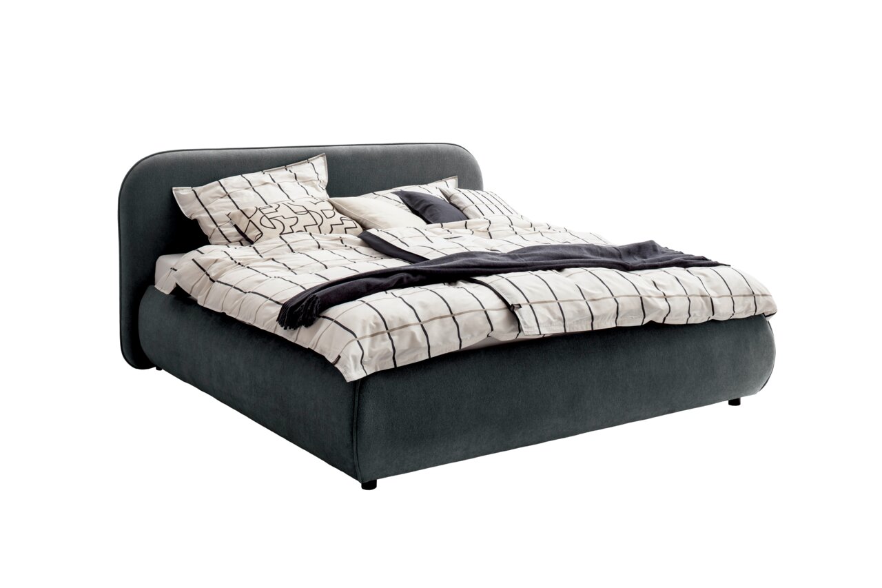 Polsterbettgestell in dunklem Stoffbezug mit gemustertem Bettzeug, seitliche Perspektive