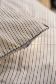 Nahaufnahme einer gestreiften Bettwäsche mit Etikett, das den Markennamen zeigt.