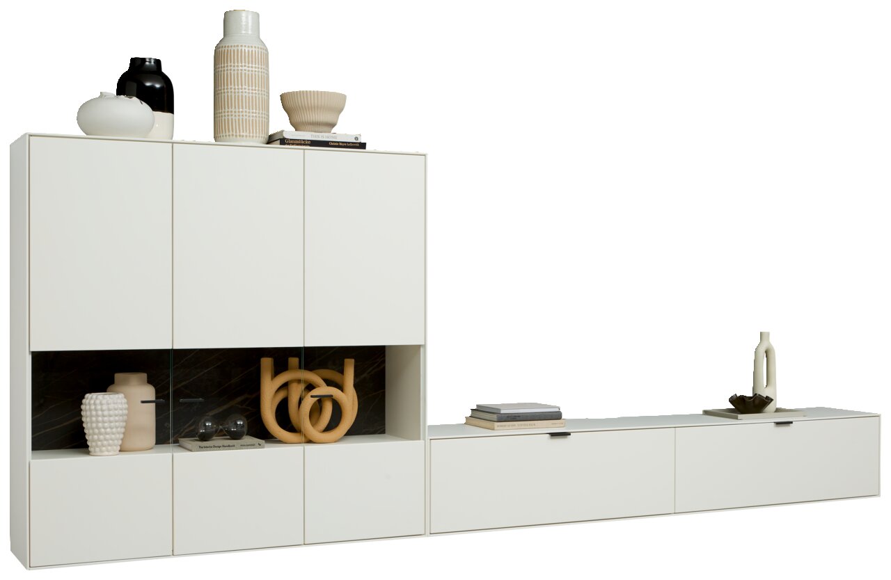 Moderne weiße Wandkombination mit mehreren Schränken und Regalen, dekoriert mit Vasen und Büchern, seitliche Perspektive.