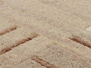 Nahaufnahme eines Wollteppichs mit beigem und braunem Muster, aus der Vogelperspektive fotografiert.