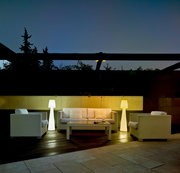 Stehleuchte LOLA 110 in einem modernen Außenbereich, umgeben von weißen Rattanmöbeln, bei Dämmerung beleuchtet.