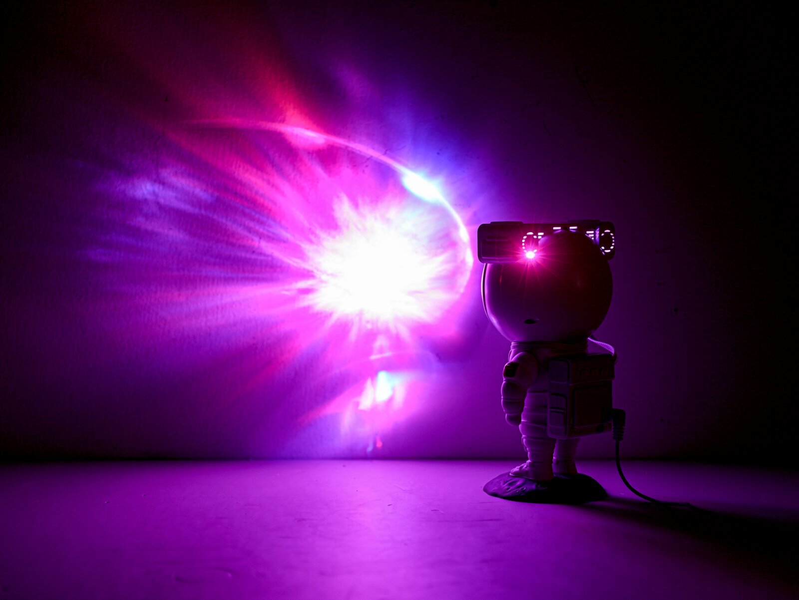 LED-Dekoleuchte in Form eines Astronauten, der bunte Lichteffekte an die Wand projiziert, seitliche Perspektive