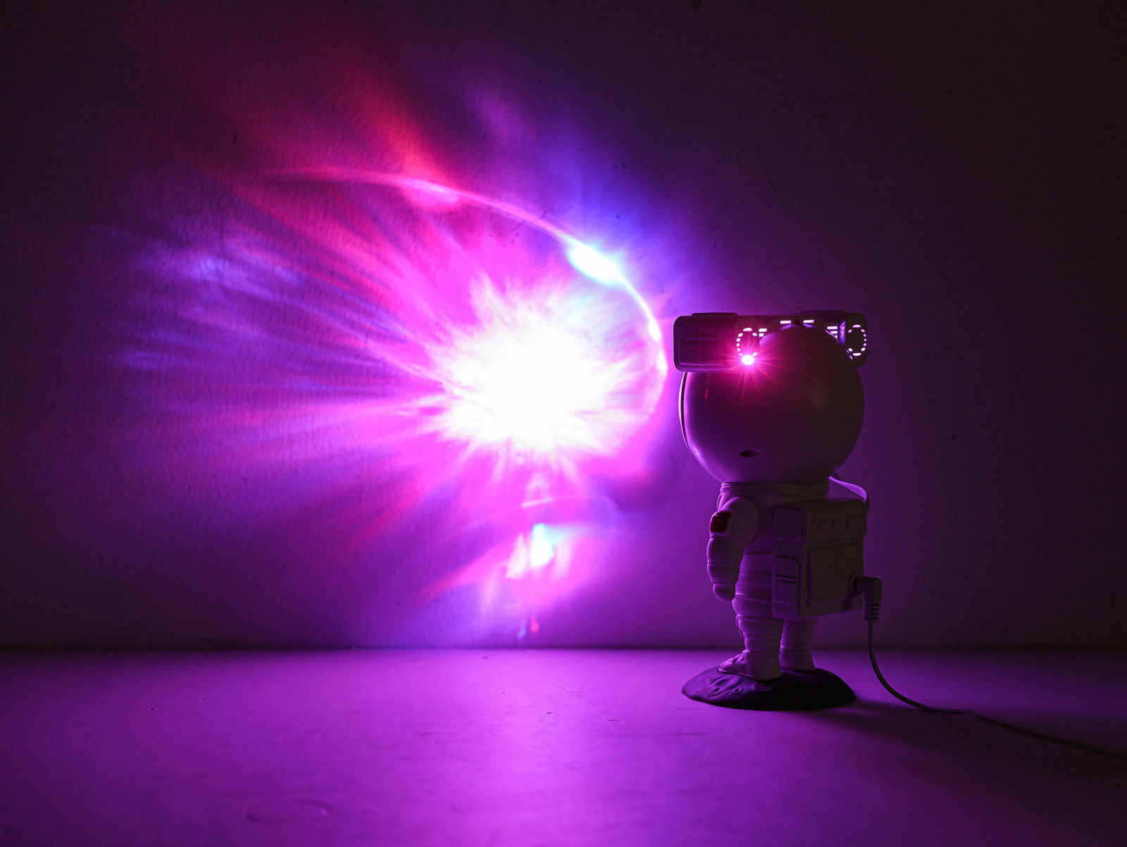 LED-Dekoleuchte in Form eines Astronauten, der bunte Lichteffekte an die Wand projiziert, seitliche Perspektive