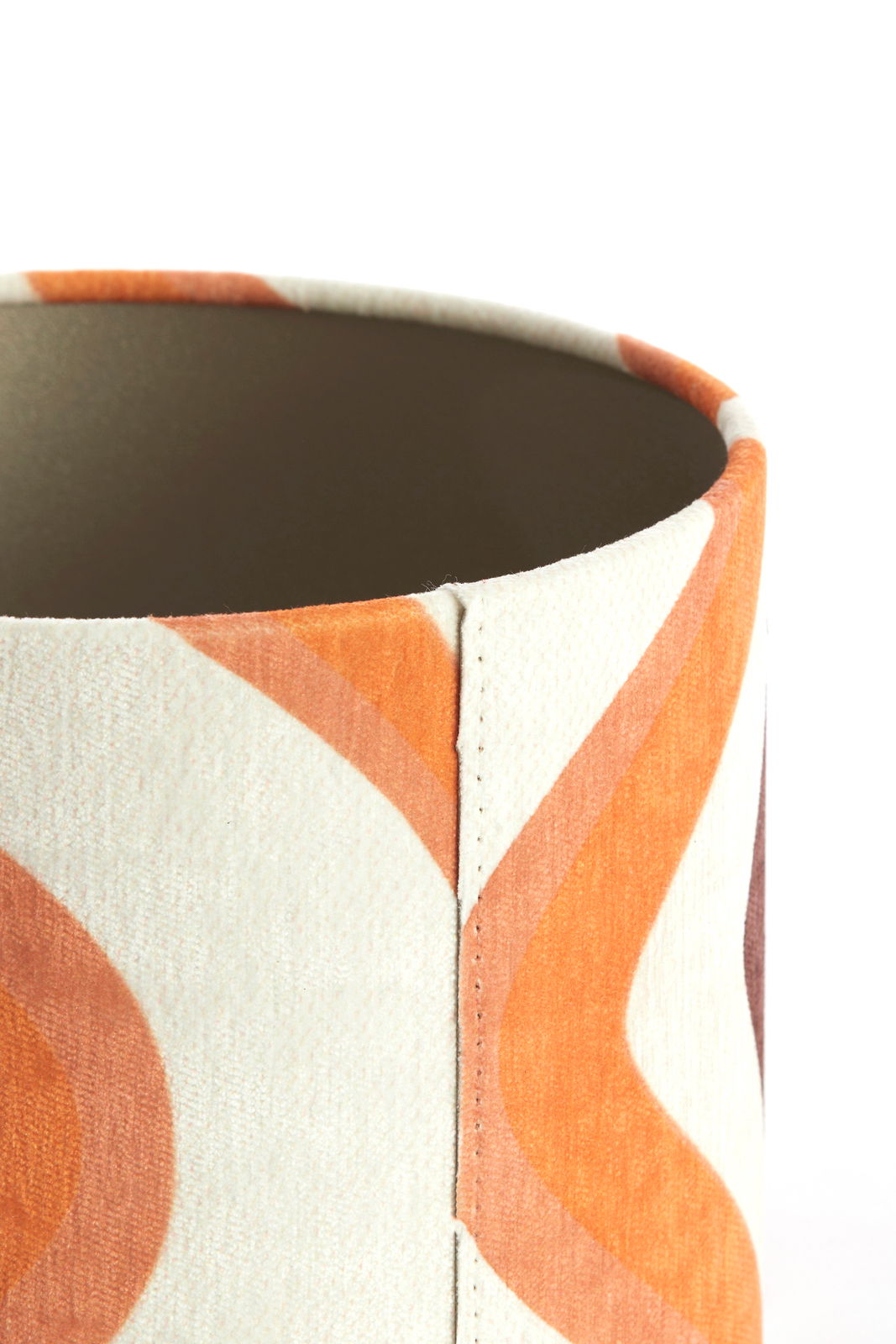 Nahaufnahme eines Lampenschirms mit orangefarbenem, wellenförmigem Muster, seitliche Perspektive.