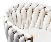 Nahaufnahme eines Sessels mit geflochtenem, cremefarbenem Polster und goldenen Akzenten, seitliche Perspektive.