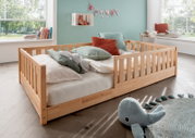 Holzbodenbett für Kinder mit Kissen und Kuscheltieren, seitliche Perspektive