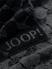 Close-up van een grijze saunadoek met ingeweven patroon en het opschrift 'JOOP!'