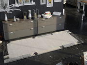 Moderner Teppich in hellen und dunklen Tönen vor einer Kommode, aus der Vogelperspektive fotografiert.