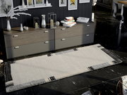 Moderner Teppich in hellen und dunklen Tönen vor einer Kommode, aus der Vogelperspektive fotografiert.