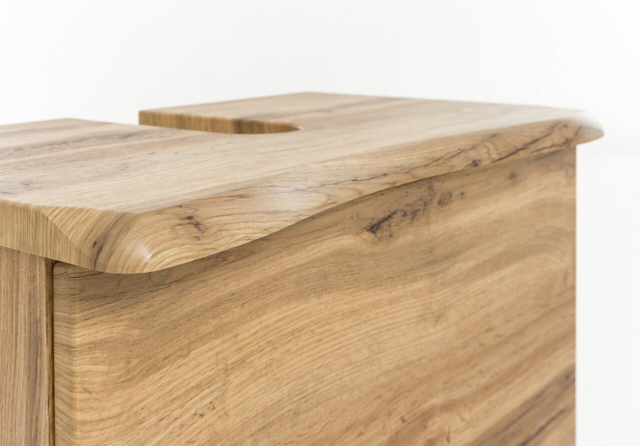 Nahaufnahme eines Waschbeckenunterschranks aus Holz mit natürlicher Maserung, seitliche Perspektive